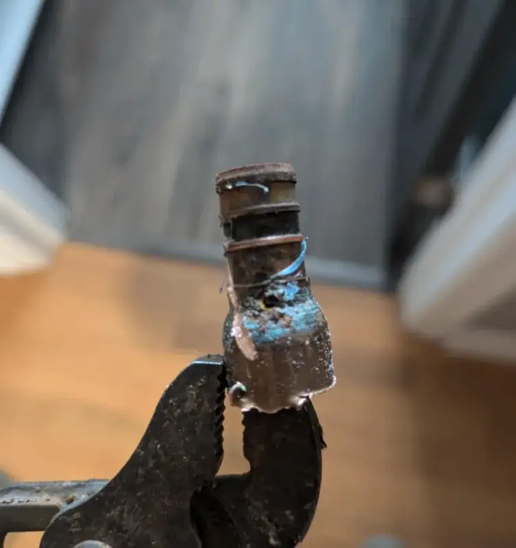 Corroded fitting held in pliers after being removed from a pipe