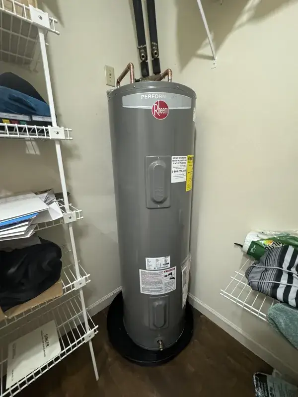 Electric tank water heater installed on a drain pan inside a closet