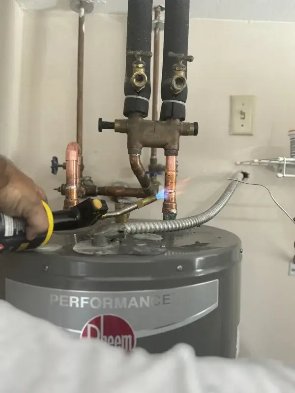 Plumber soldering copper connections on top of a new Rheem water heater
