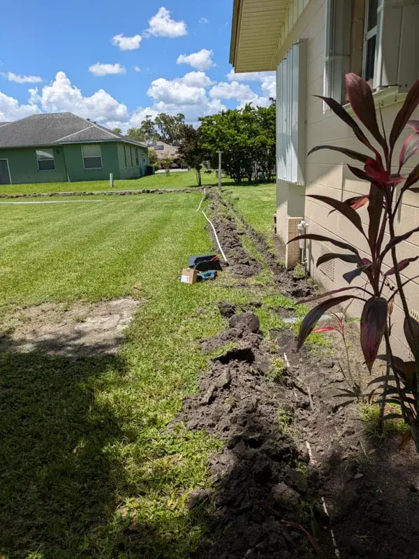 Water line trench dug across a lawn beside a Southwest Florida home